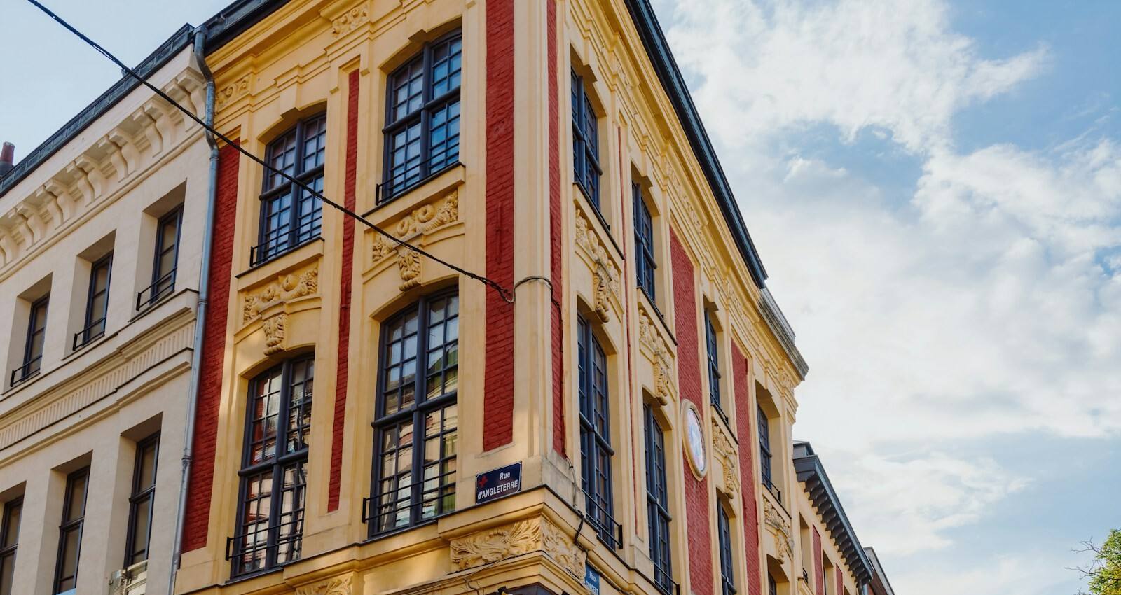 La façade jaune et rouge d'un immeuble du Vieux-Lille, à l'angle de deux rues.