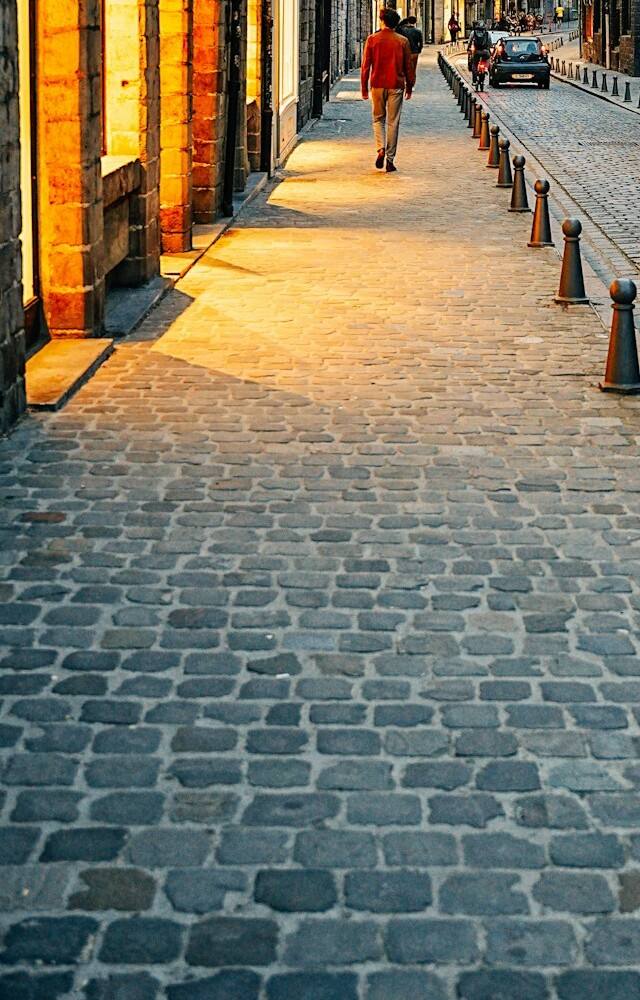 Des vitrines éclairées le long d'une rue pavée du Vieux-Lille, le soir.